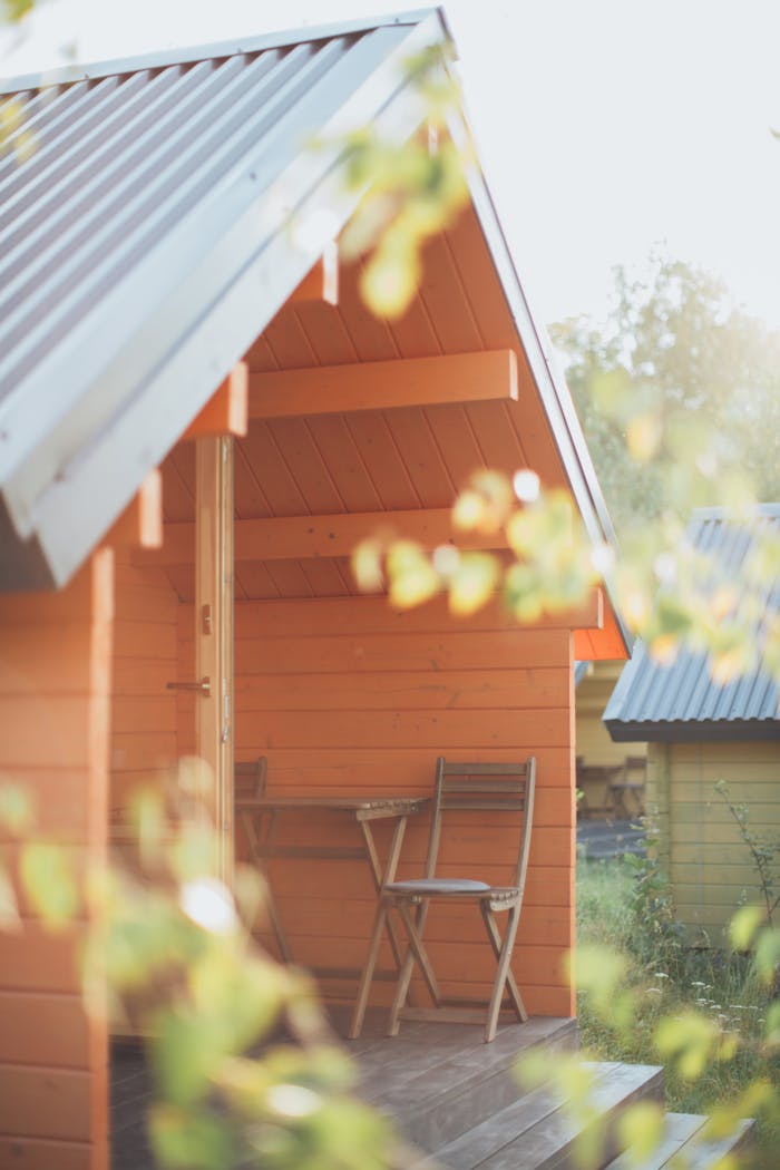 Charming wooden cabin exterior with a sunlit veranda, perfect for summer relaxation.